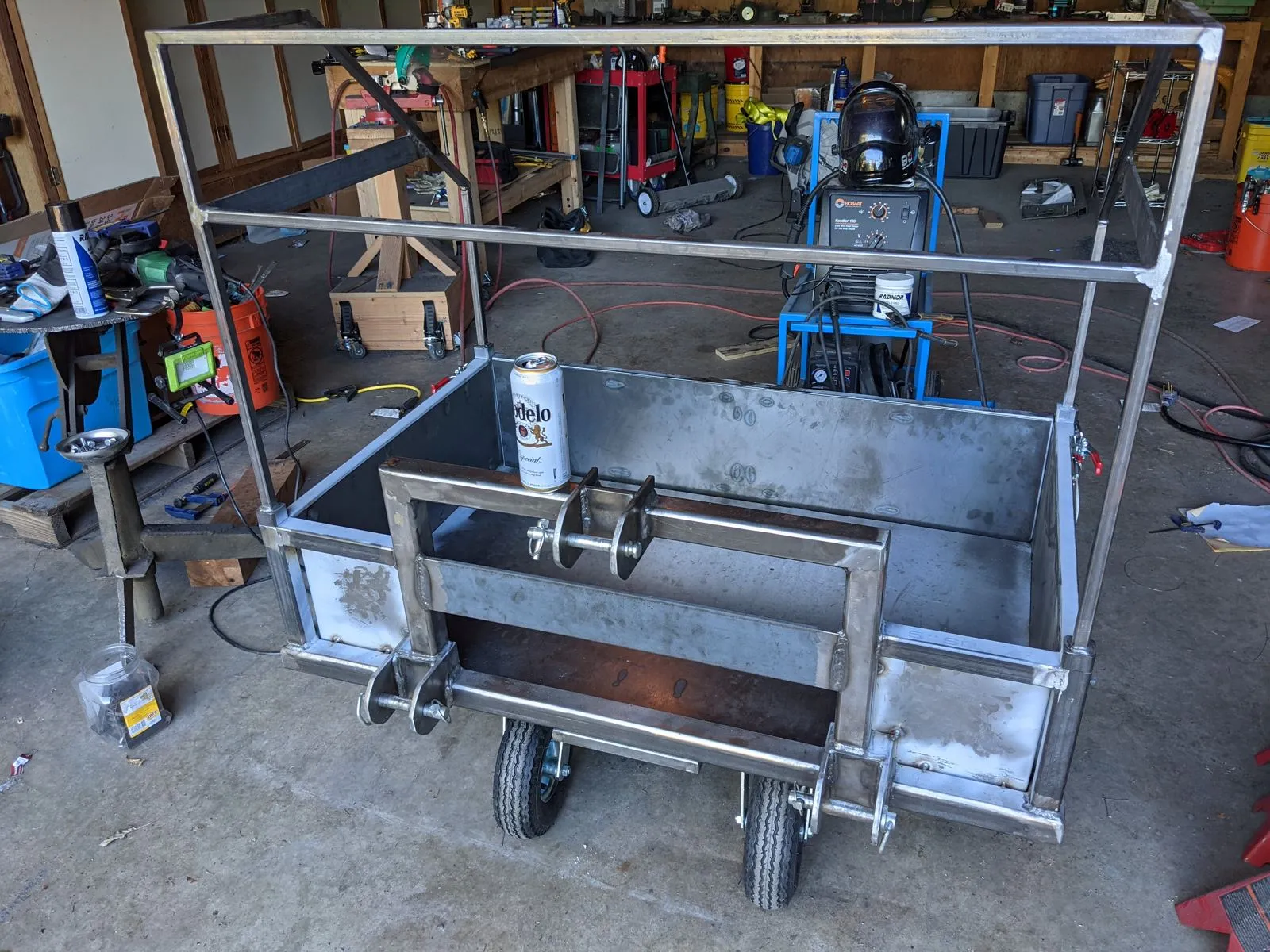 The fabricated carry-all, bare steel and ready for finishing, with a Modelo tallboy for scale