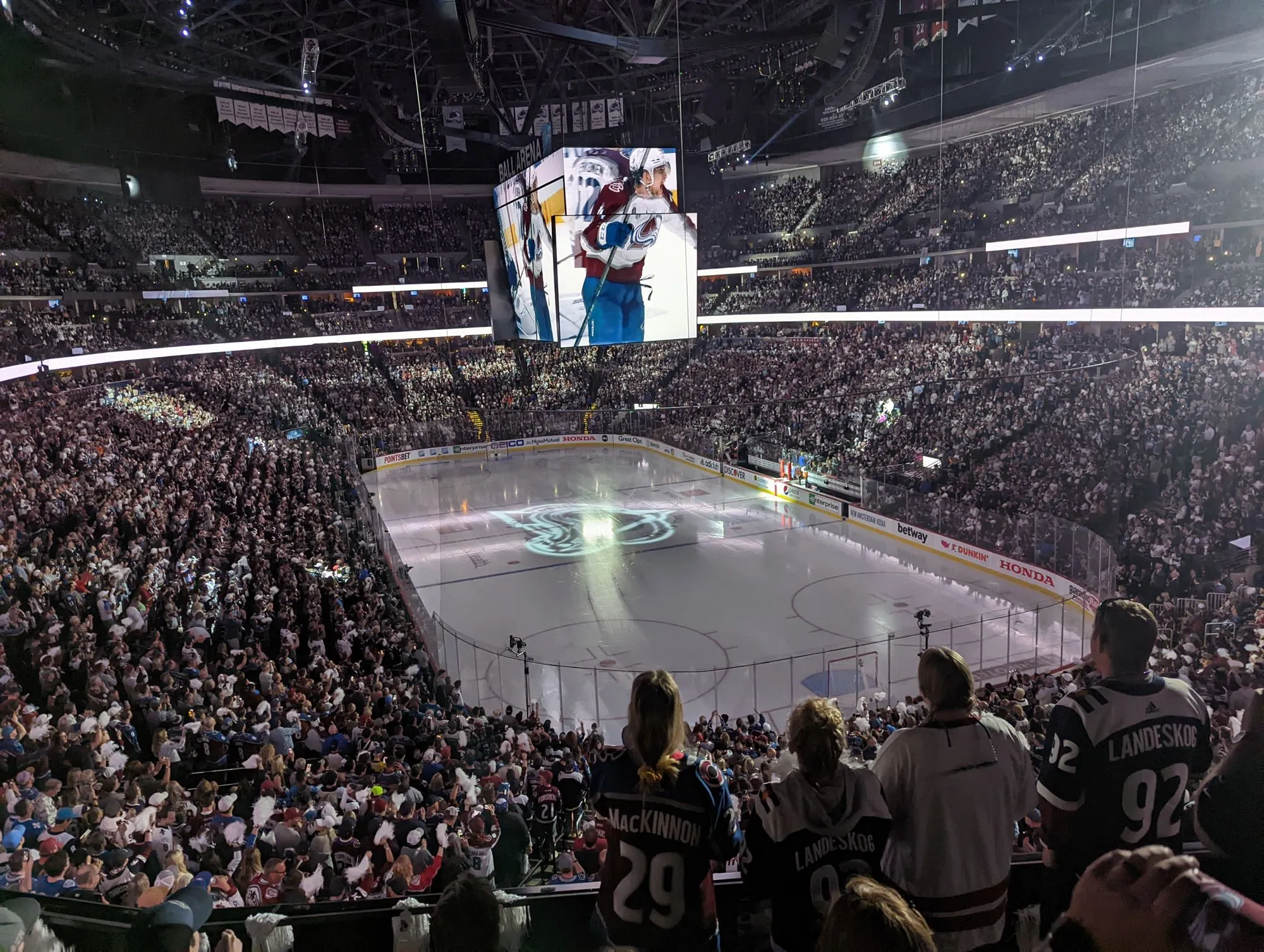 Inside the arena for an Avalanche game, with a packed crowd and the ice lit up