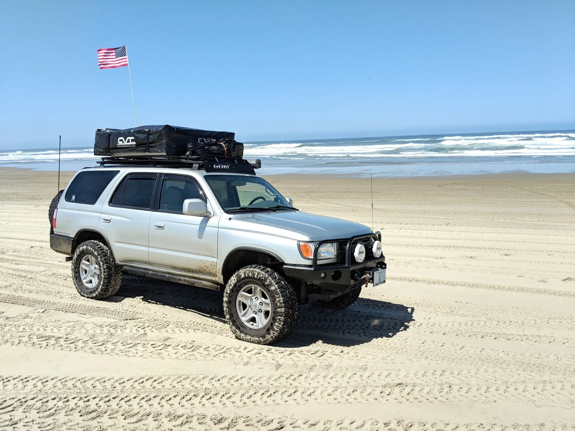 The 4Runner on the beach with the rooftop tent packed on the roof rack