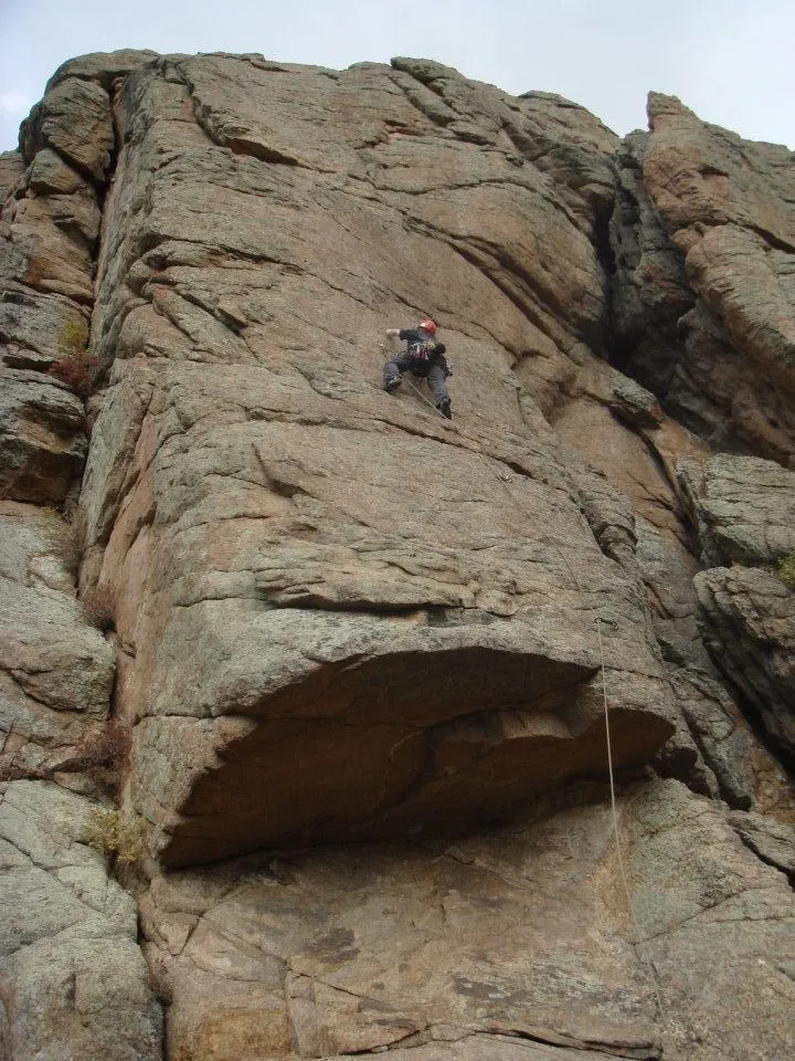 James leading a rock climb up a face below a large roof